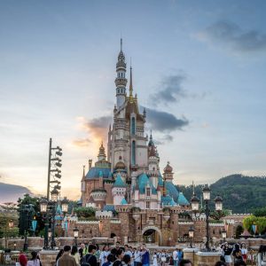 Magical fairytale castle at Hong Kong Disneyland with crowds at sunset.